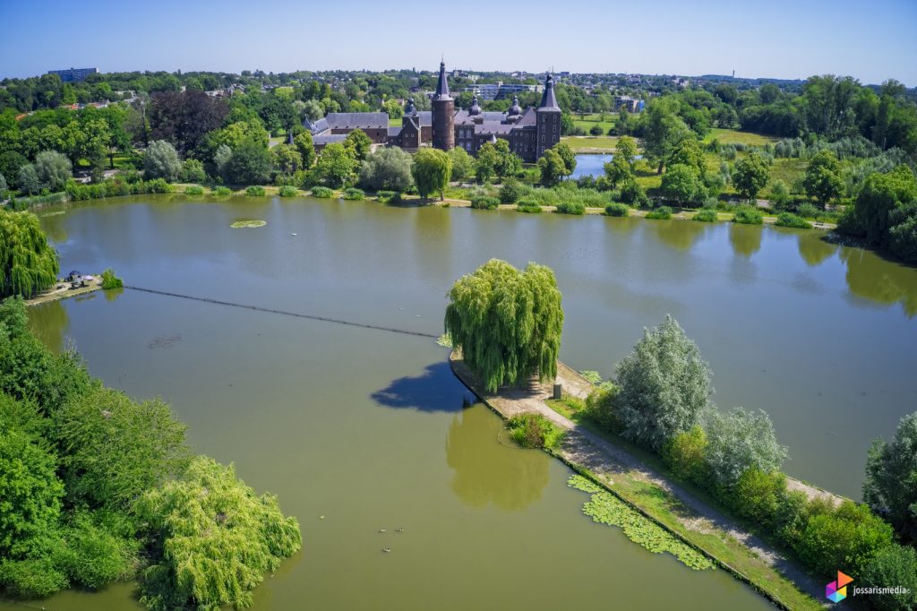 a body of water with a path and trees and buildings in the background