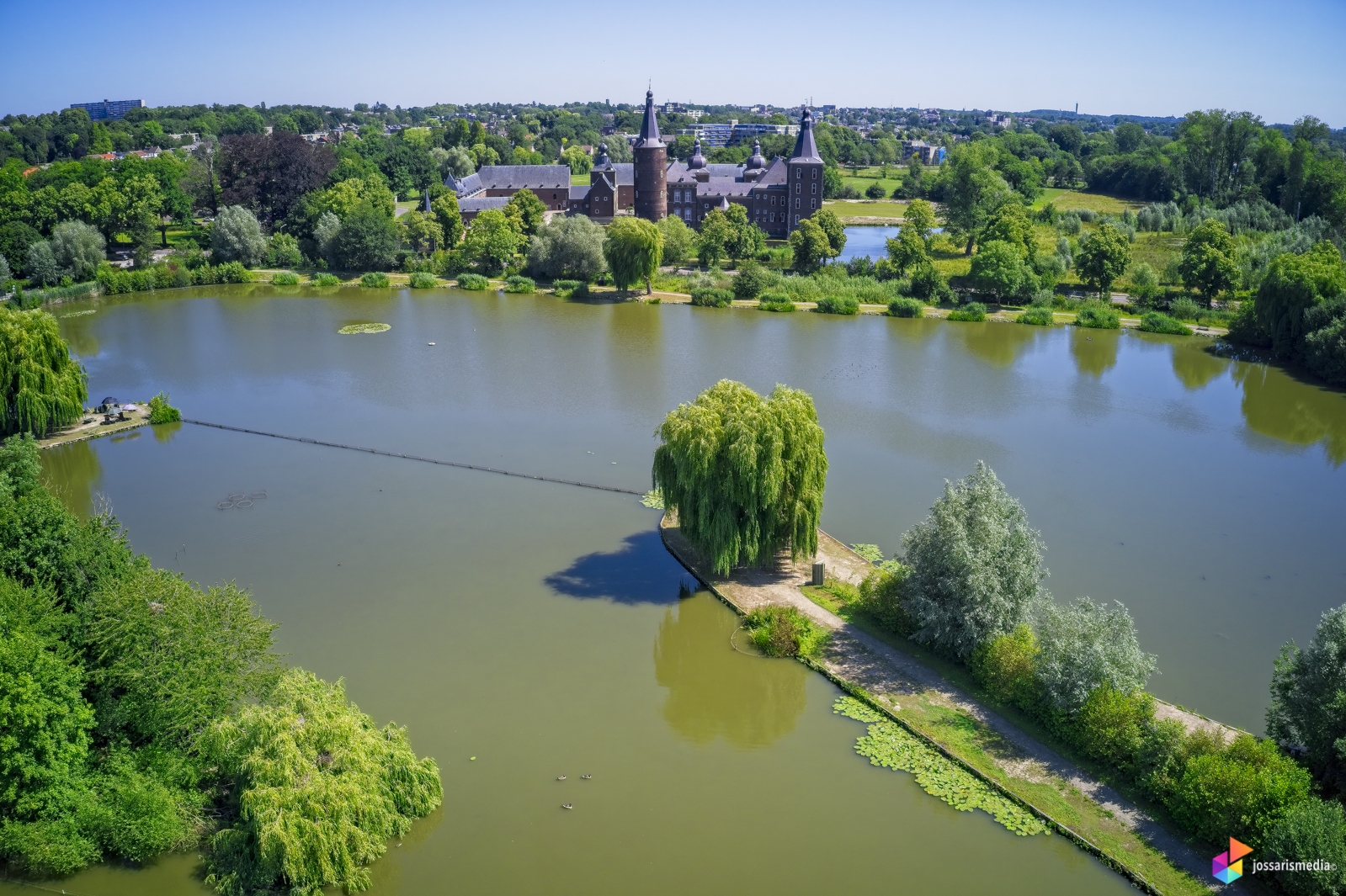 a body of water with a path and trees and buildings in the background
