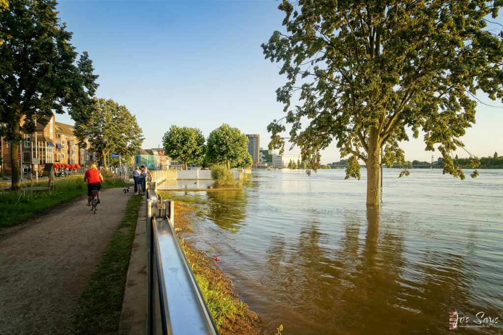 a flooded area with people walking on a bike path