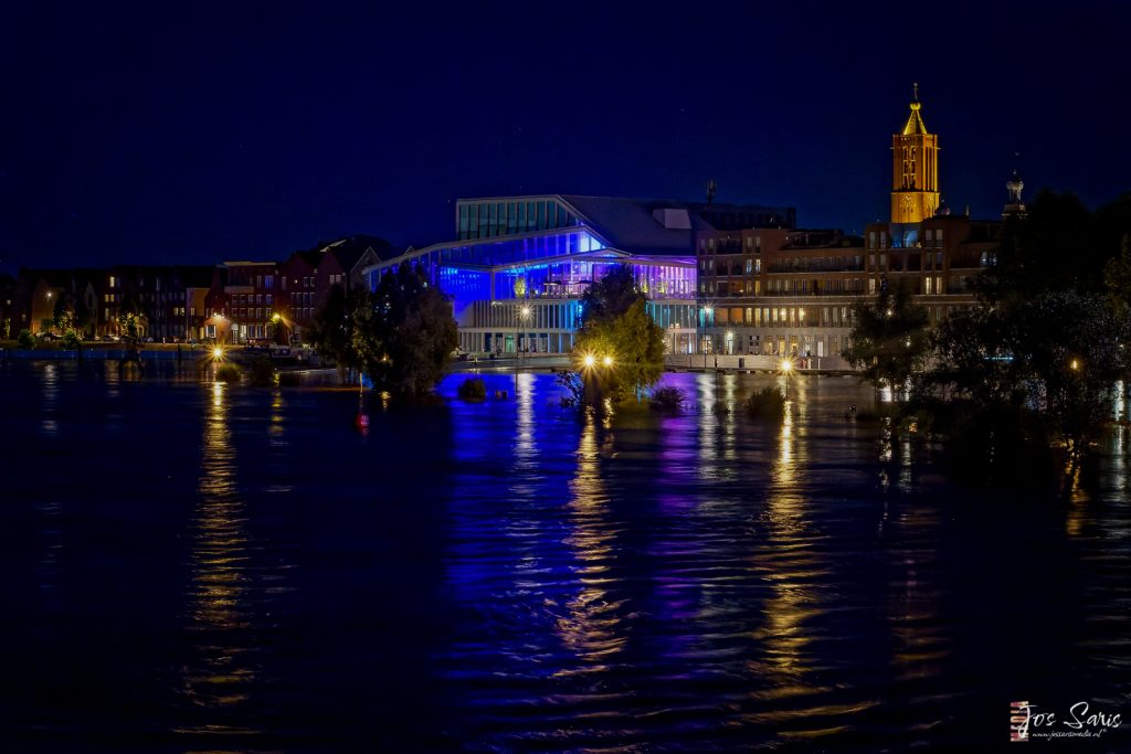 a building with lights on the side of the water