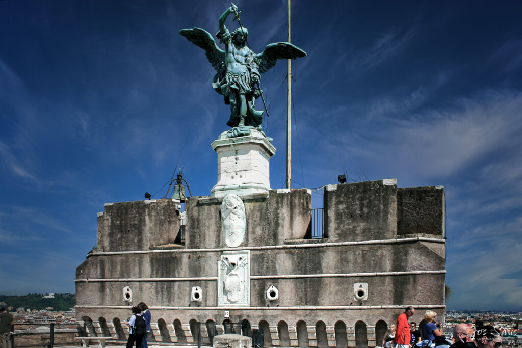 a statue of a man with wings and a sword on top of a stone building