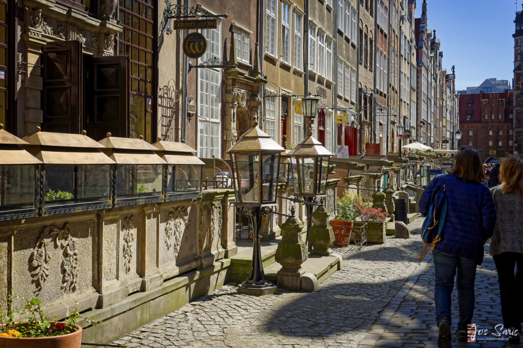 a person on a sidewalk with a lamp post and a man on a bicycle