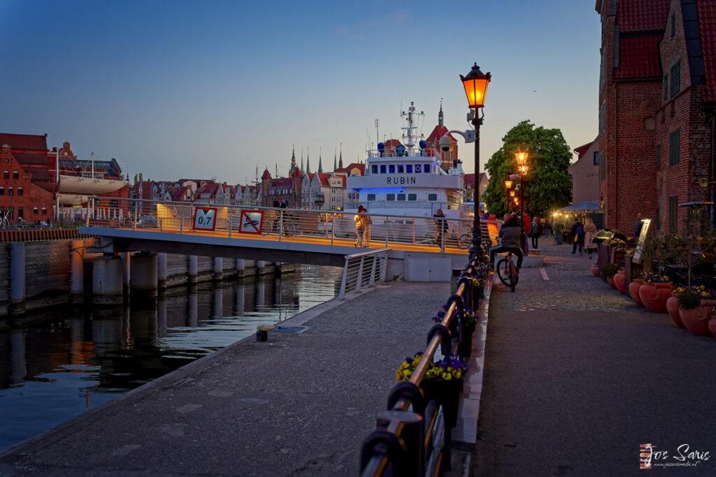 a bridge over water with a boat and buildings in the background