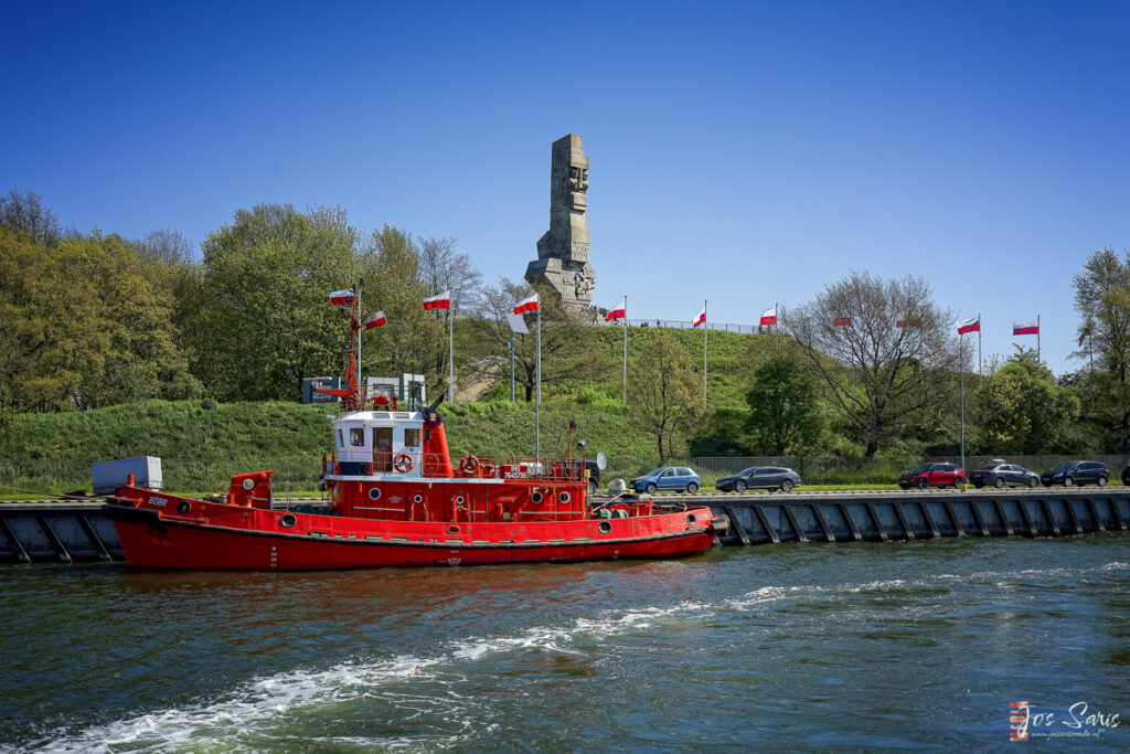 a red boat on water with a monument in the background