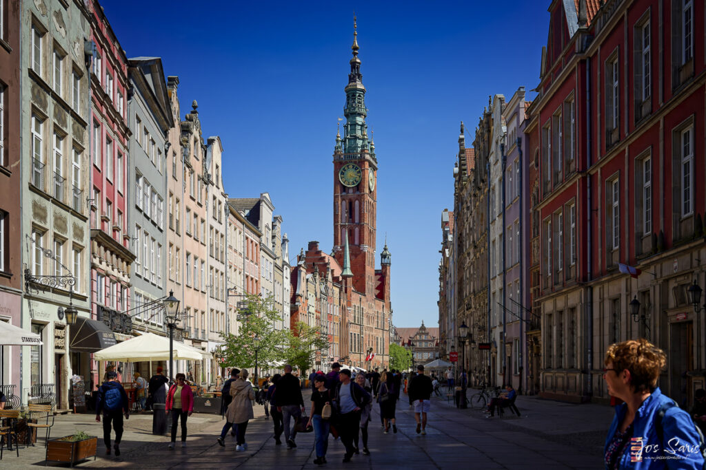 a group of people walking down a street with a clock tower