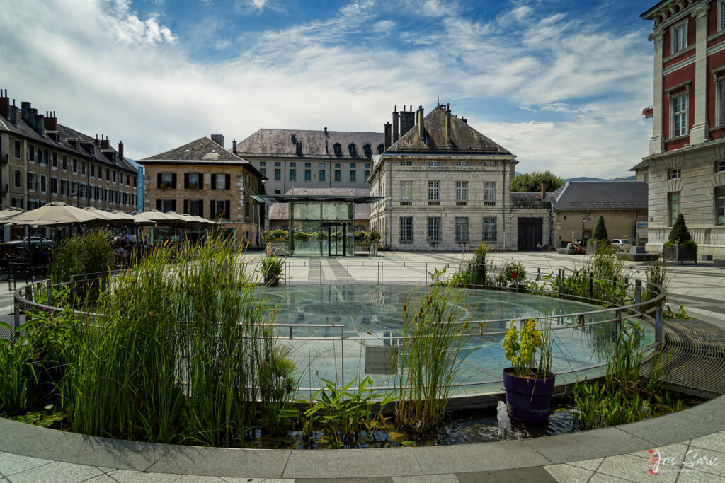 a fountain in a courtyard with buildings in the background