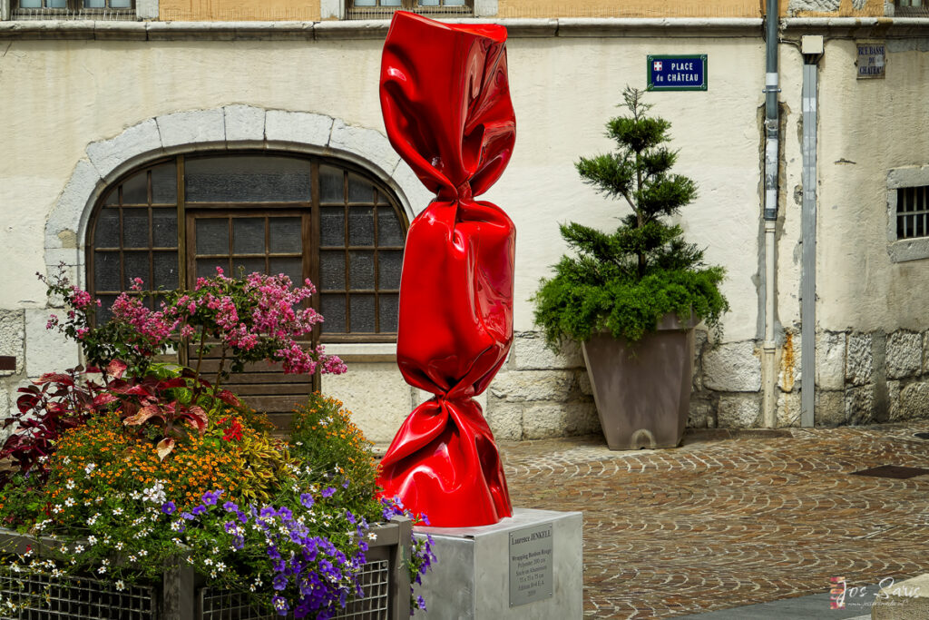 a red wrapped candy sculpture in front of a building