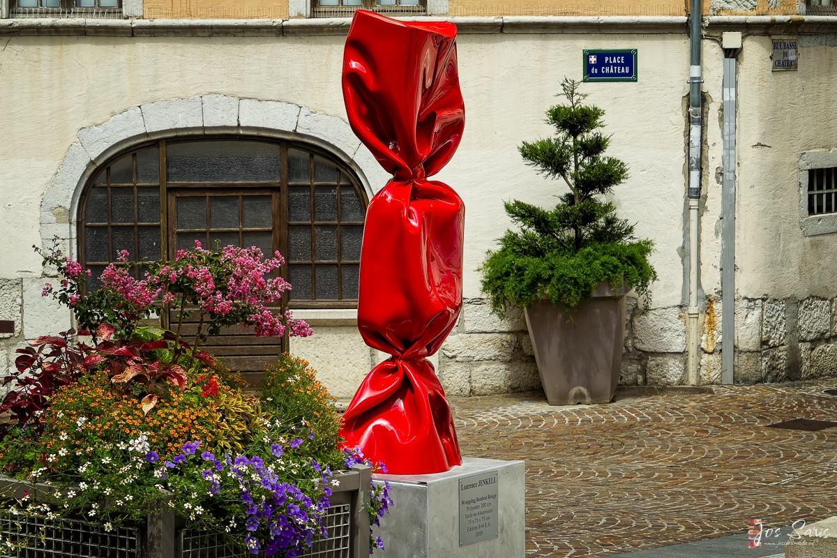 a red wrapped candy sculpture in front of a building