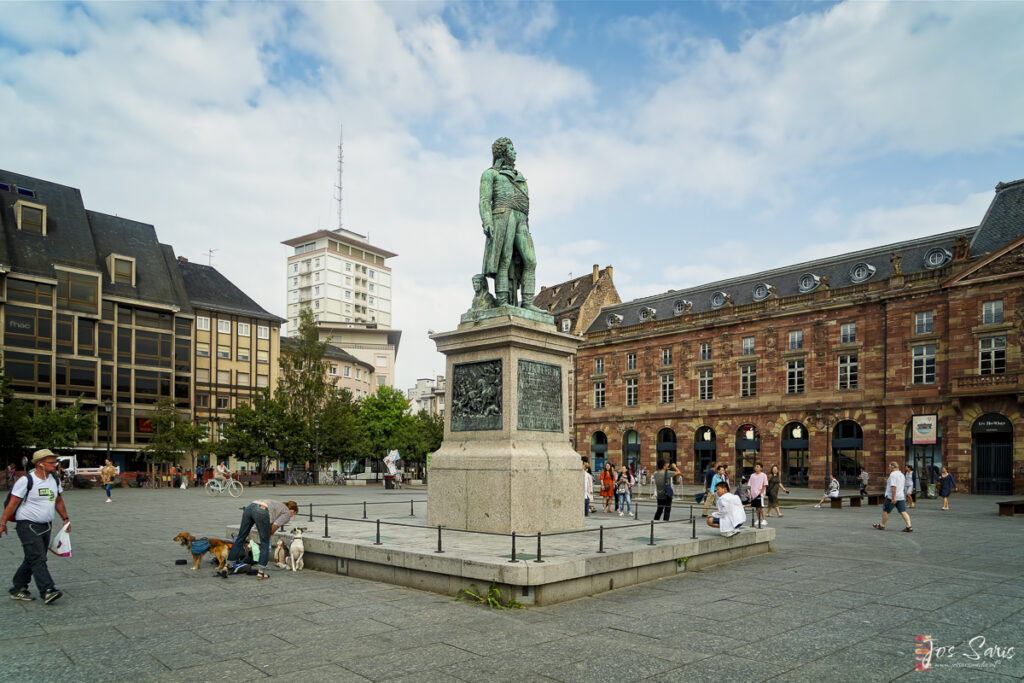 a statue of a man in a square with people and buildings