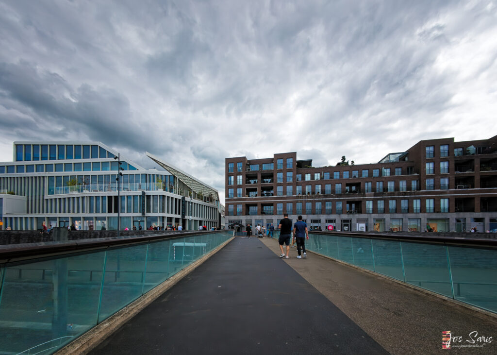 a group of people walking on a walkway with a pool of water